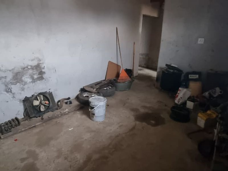 An unfinished garage space featuring raw plaster walls and a concrete floor, currently used for storage.