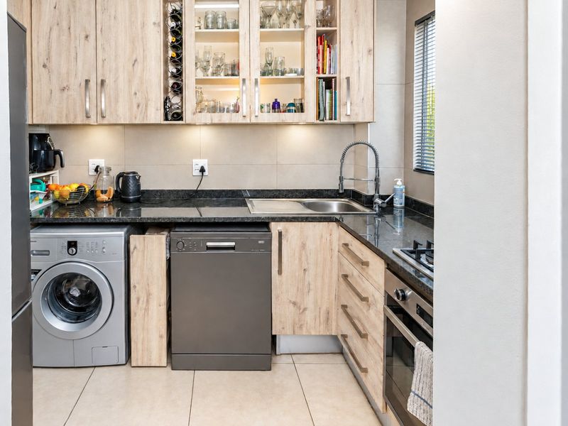 Modern kitchen featuring light wood-finish cabinetry, granite countertops, integrated appliances, and a functional layout with ample storage and task lighting.