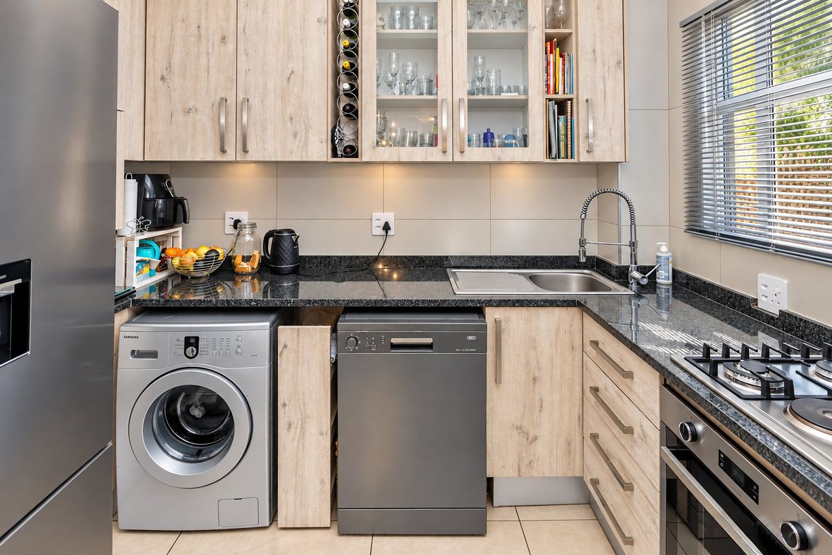 Modern kitchen featuring light wood-grain cabinetry, dark granite countertops, integrated appliances, and a functional layout with ample storage and task lighting.