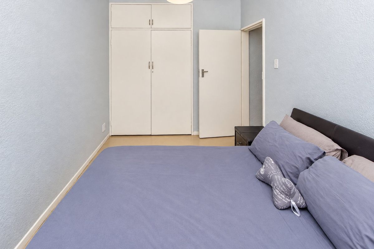 A functional bedroom featuring built-in cupboards and neutral wall finishes, providing a practical and comfortable living space.