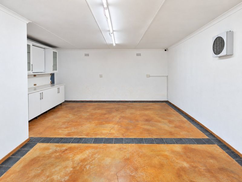 Spacious garage featuring concrete flooring with a tiled border, built-in storage cabinetry, and a wall-mounted air conditioning unit.