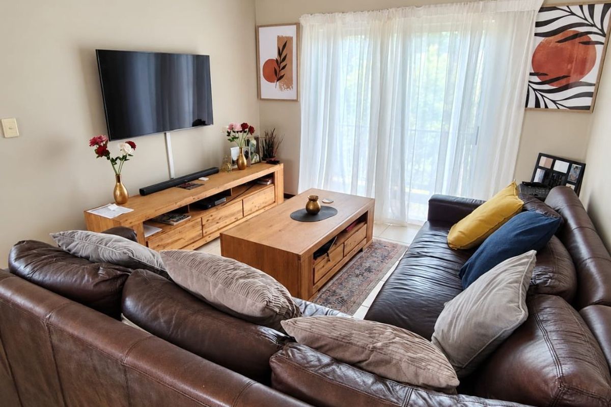 A comfortable living room featuring tiled flooring and a sliding glass door that provides natural light.