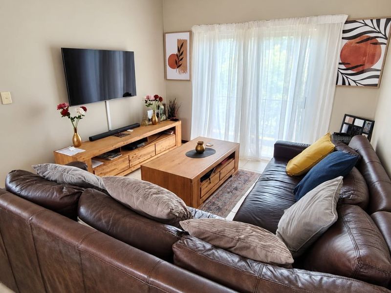A comfortable living room featuring tiled flooring and a sliding glass door that provides natural light.