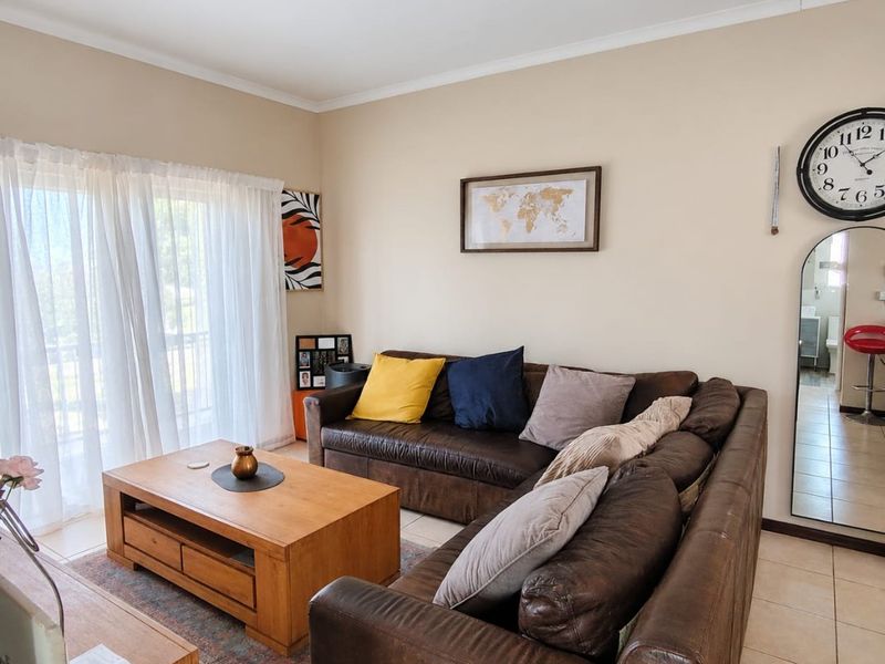 A comfortable living room featuring ceramic floor tiles and a large sliding glass door that provides access to the outdoor area.