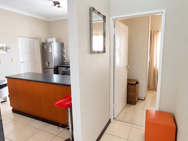 An open-plan living area featuring a kitchen island with a dark countertop and tiled flooring, leading into an adjacent room through a doorway.