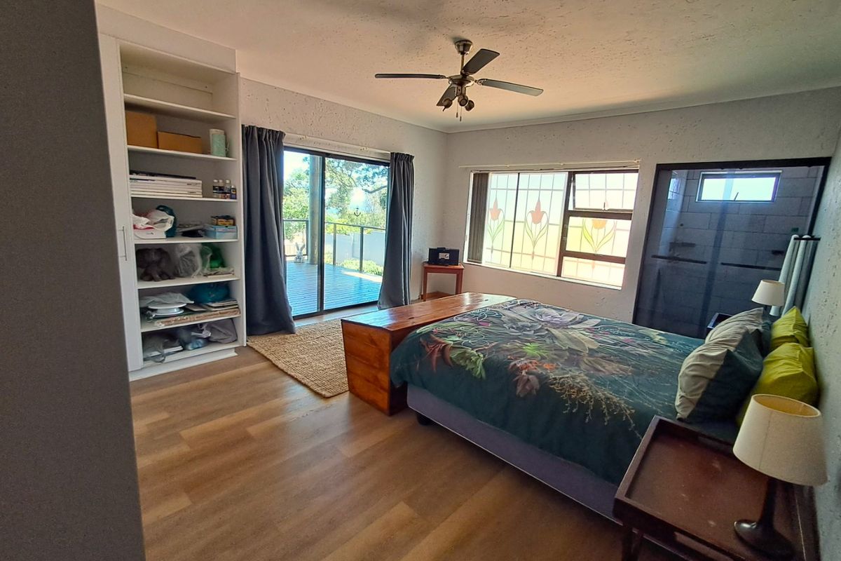 Spacious bedroom featuring laminate flooring, built-in shelving, a ceiling fan, and sliding glass doors providing access to an outdoor deck area.