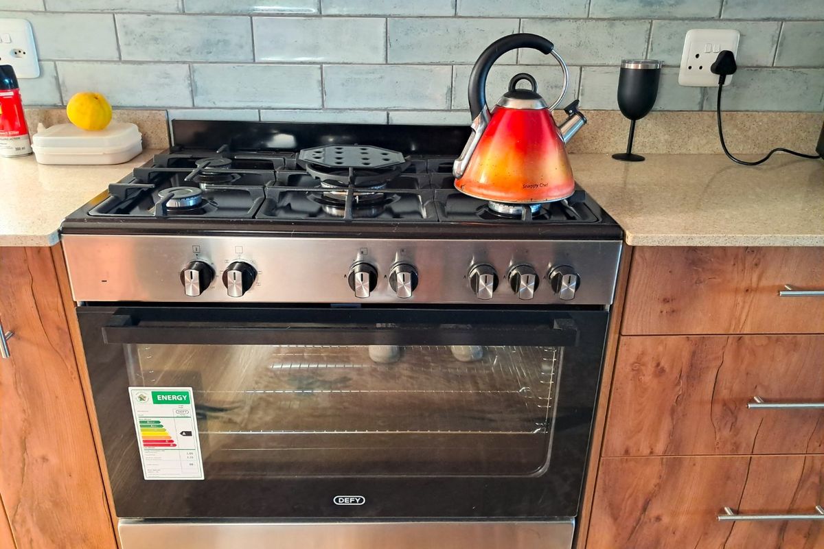 A well-maintained kitchen area featuring a stainless steel Defy gas stove and oven, complemented by stone countertops and a stylish subway tile backsplash.