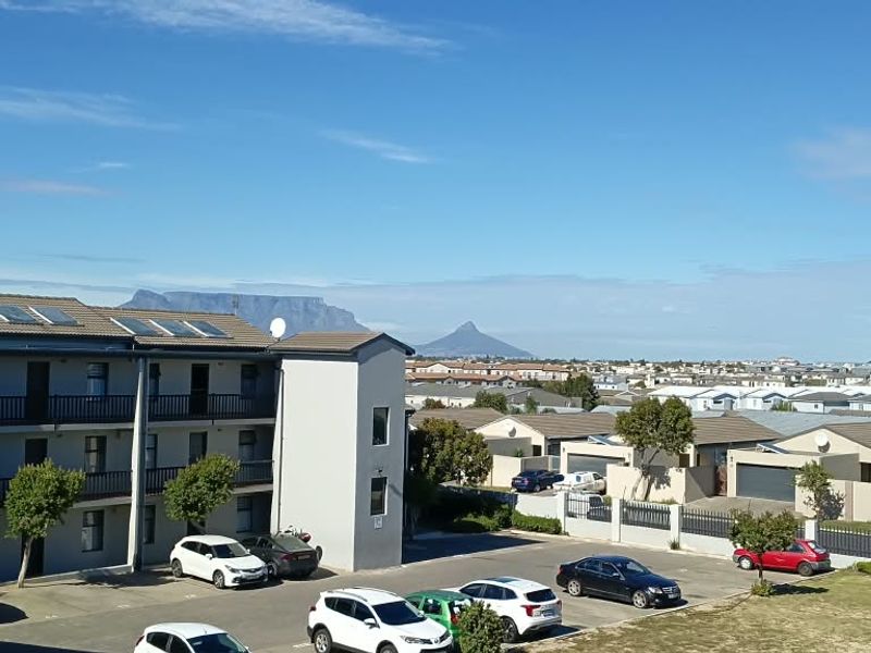 Elevated view overlooking the apartment complex parking area with Table Mountain visible in the distance.