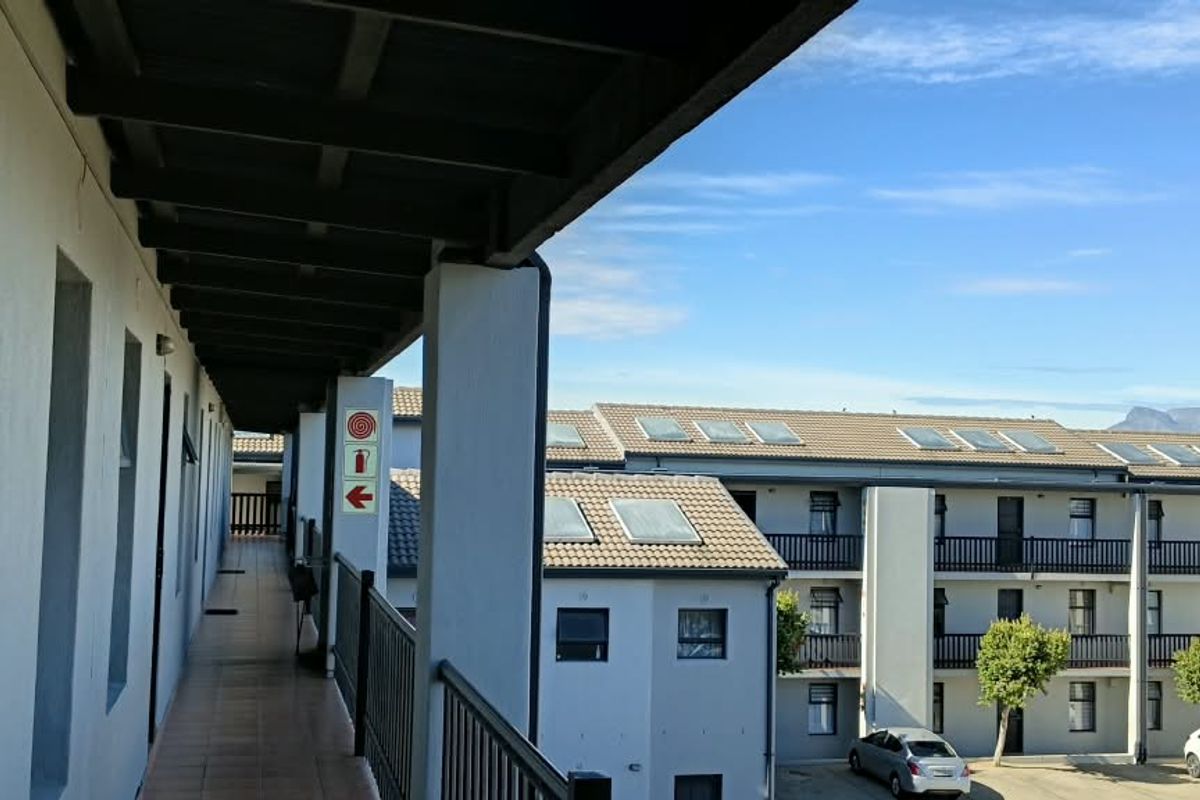 An exterior covered walkway and balcony area overlooking the apartment complex courtyard with views of the surrounding neighborhood.