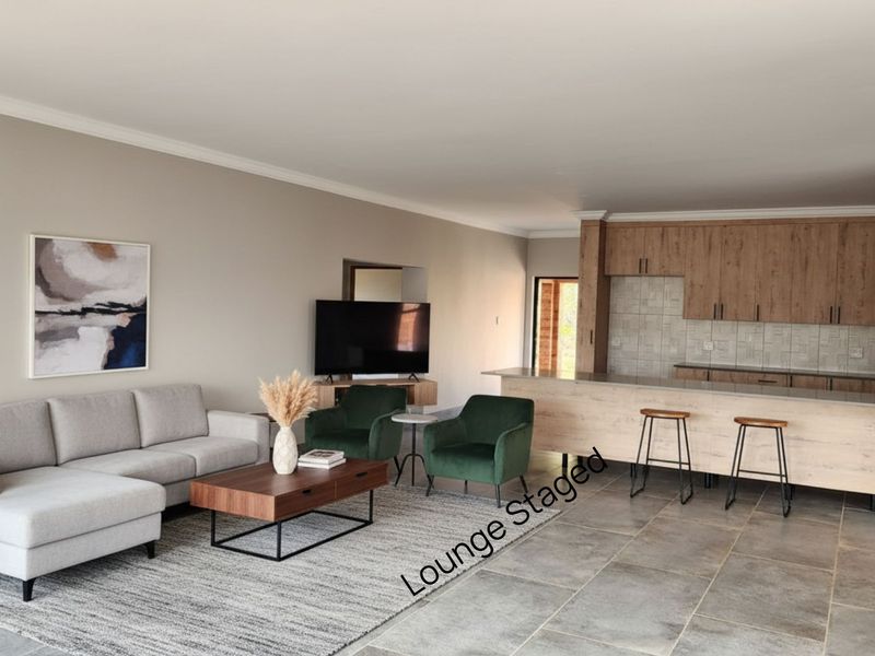 Spacious open-plan living area featuring a modern kitchen with wood-look cabinetry, a central island, and durable tiled flooring throughout.
