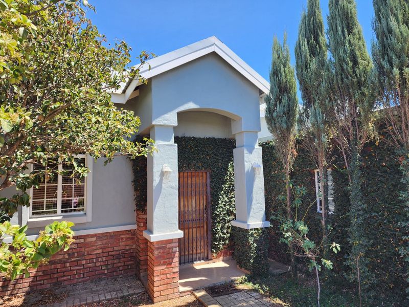 Front entrance of the townhouse featuring a covered porch, brick detailing, and established climbing ivy on the exterior walls.