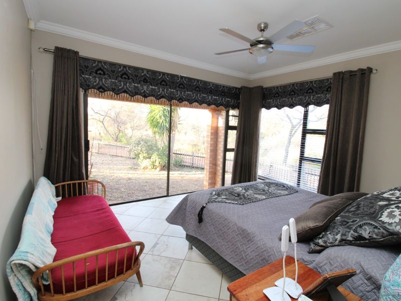 Spacious bedroom featuring tiled flooring, a ceiling fan, and large sliding glass doors that provide ample natural light and access to the outdoors.