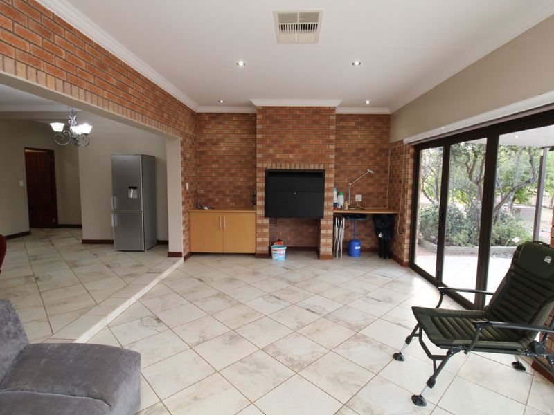 Spacious living area featuring an exposed brick wall, built-in fireplace, tiled flooring, and large sliding glass doors providing access to the outdoor space.