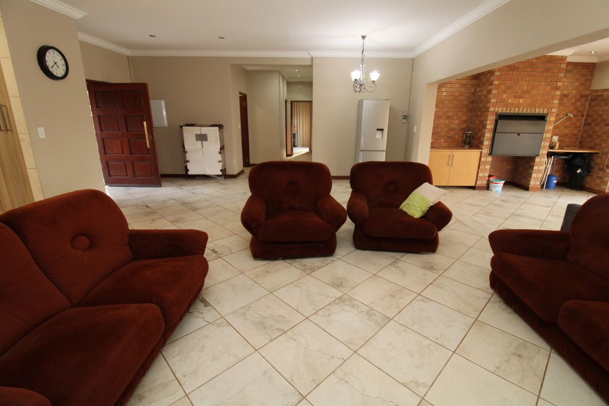 Spacious living area featuring tiled flooring, a prominent brick fireplace, and neutral wall finishes with recessed lighting.