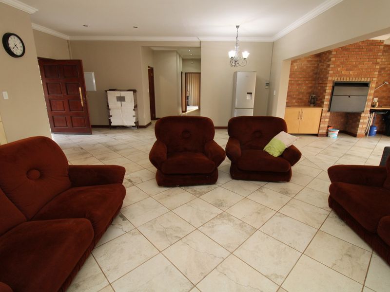 Spacious living area featuring tiled flooring, a prominent brick fireplace, and neutral wall finishes with recessed lighting.
