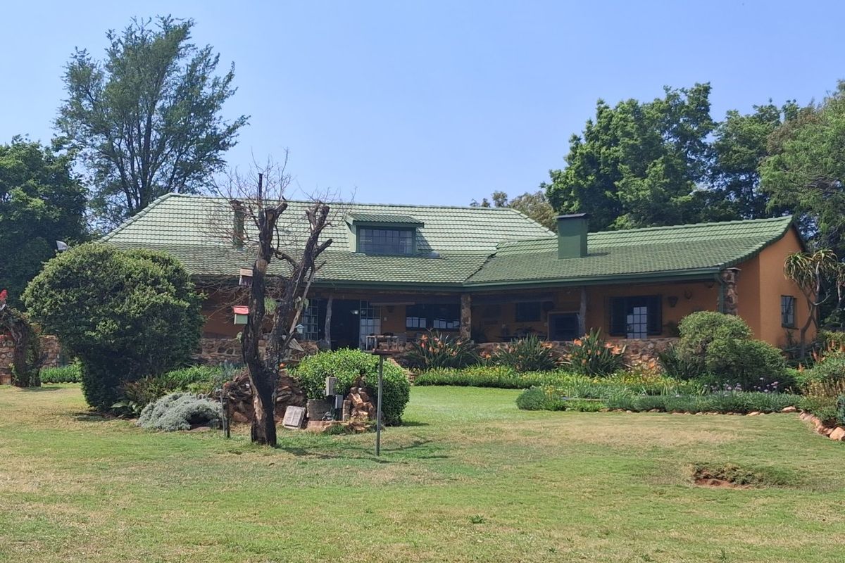 A charming single-story home featuring a green tiled roof, stone accents, and a spacious covered patio overlooking a well-maintained garden.