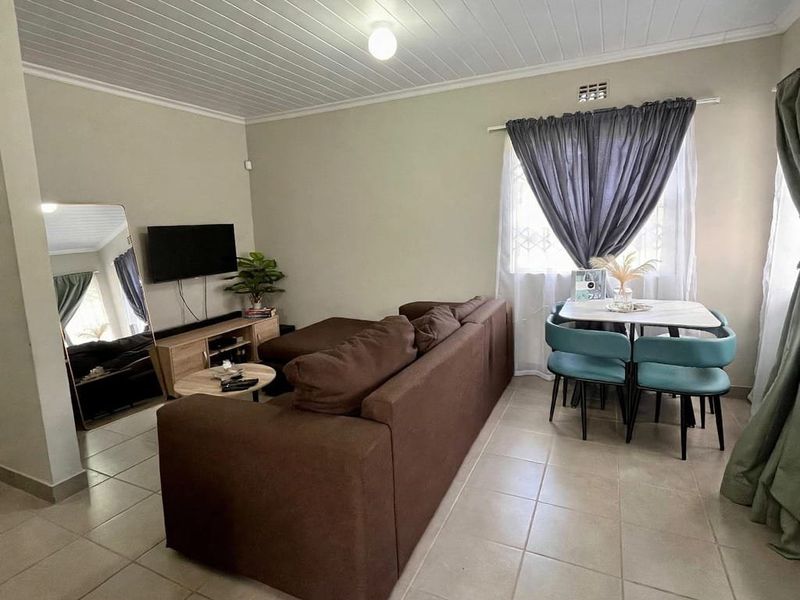 An open-plan living and dining area featuring tiled flooring and a tongue and groove ceiling, providing a functional and versatile living space.