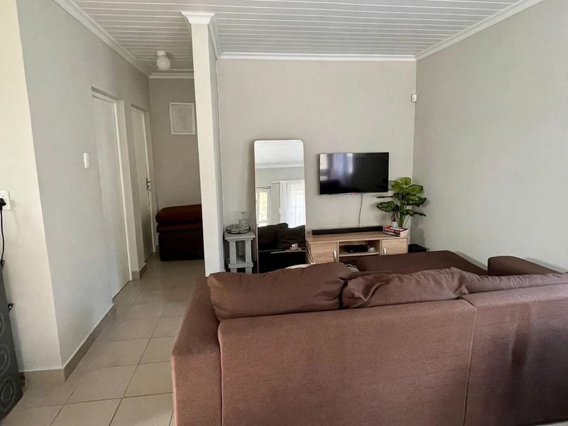 A living room featuring tiled flooring and a white tongue and groove ceiling with coving, providing a neutral base for interior design.