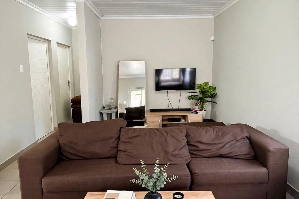 A well-maintained living room featuring tiled flooring, a classic tongue and groove ceiling with coving, and neutral wall finishes.
