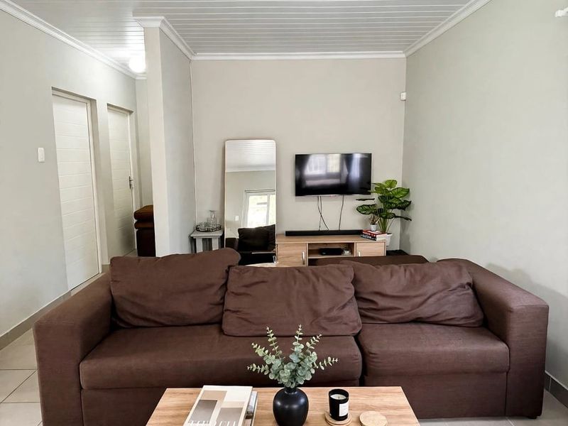 A well-maintained living room featuring tiled flooring, a classic tongue and groove ceiling with coving, and neutral wall finishes.