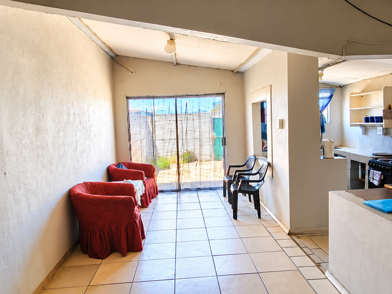 Open-plan living and kitchen area featuring tiled flooring, a functional kitchen counter with stove, and direct access to the exterior via sliding doors.
