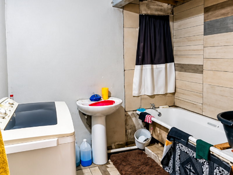 A bathroom featuring a pedestal basin and bathtub, currently requiring significant finishing work on walls, ceiling, and tiling to complete the space.