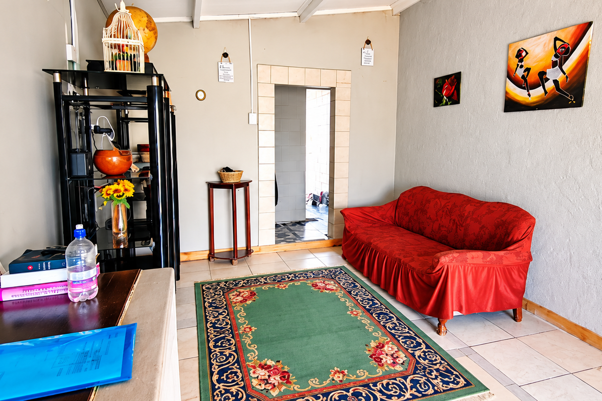 A living room featuring tiled flooring and a central doorway leading to an adjacent space.