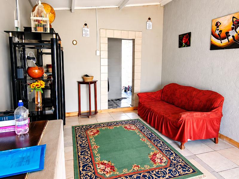 A living room featuring tiled flooring and a central doorway leading to an adjacent space.