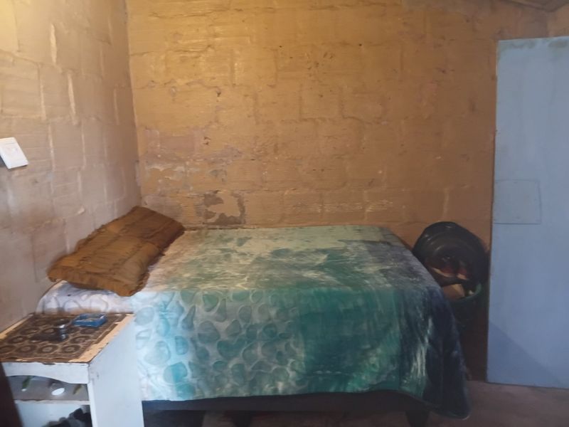 A bedroom featuring exposed concrete block walls in need of finishing and maintenance.