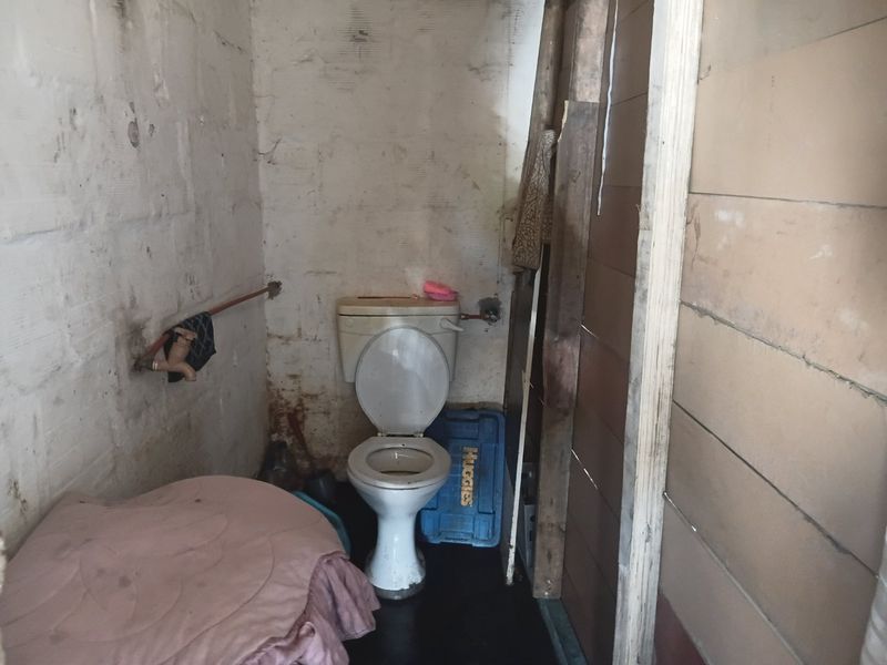 A basic bathroom space featuring a toilet and exposed plumbing, requiring significant renovation and finishing to improve the overall condition and functionality.