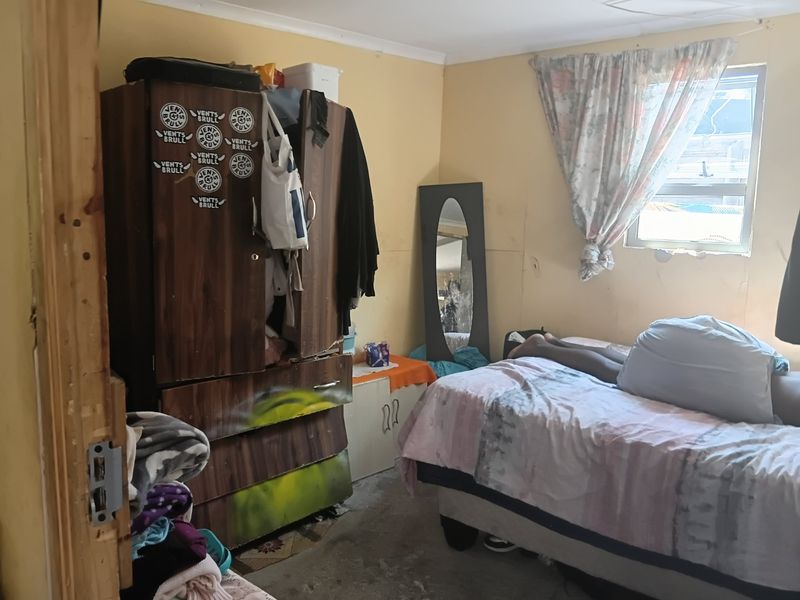 A bedroom featuring a window and basic wall finishes, currently requiring maintenance and cosmetic updates to improve the overall condition of the space.