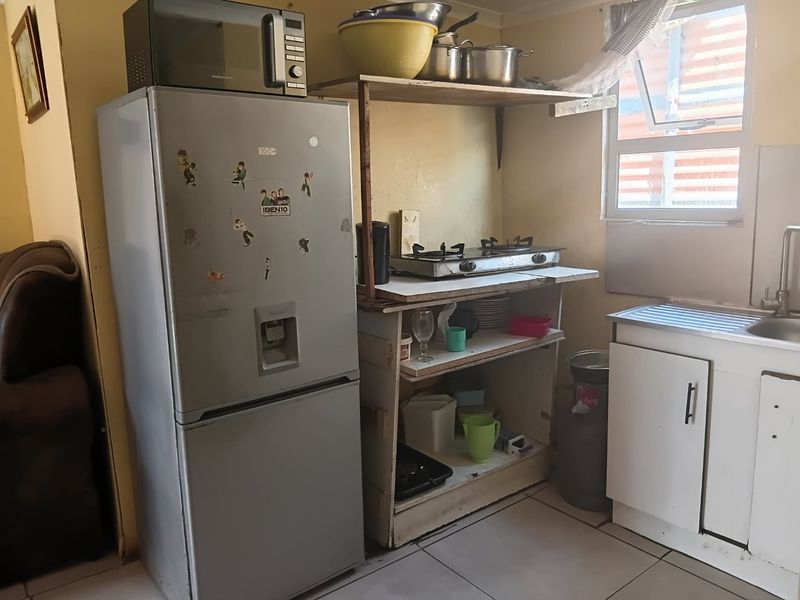 A compact kitchen area featuring a stainless steel sink, gas hob, and basic cabinetry, requiring cosmetic updates to improve functionality and aesthetic appeal.