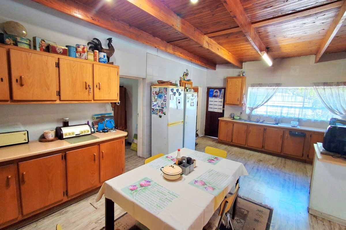 Spacious kitchen featuring wooden cabinetry, exposed timber ceiling beams, and a functional layout with ample counter space and a double basin sink.