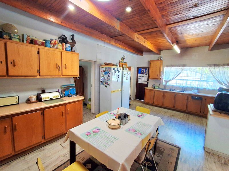 Spacious kitchen featuring wooden cabinetry, exposed timber ceiling beams, and a functional layout with ample counter space and a double basin sink.