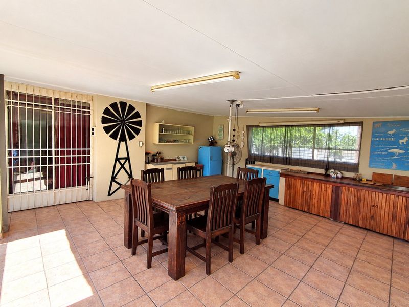 Spacious covered patio area featuring tiled flooring, built-in wooden cabinetry, and secure access, offering a versatile space for outdoor dining and entertainment.
