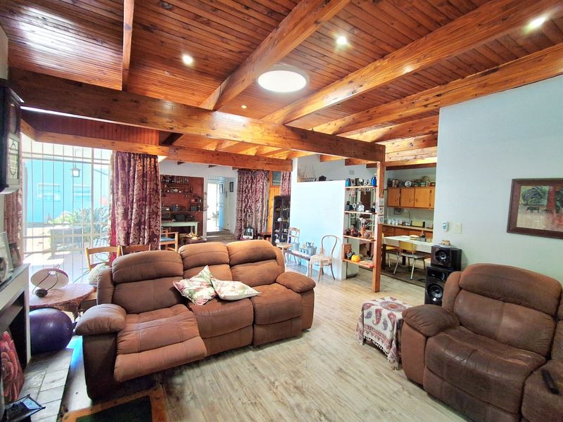 Spacious open-plan living area featuring exposed timber beams, a vaulted tongue and groove ceiling, and a skylight, creating a warm and rustic atmosphere.