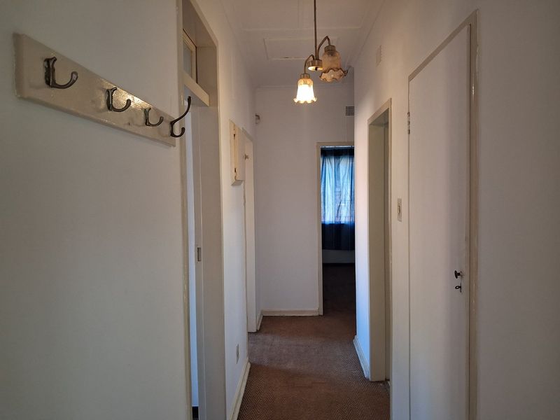 A functional residential hallway featuring carpeted flooring, multiple internal doors, and a central ceiling light fixture, providing access to various rooms within the home.