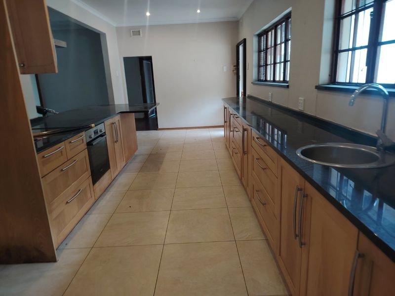 Spacious kitchen featuring extensive wooden cabinetry, dark granite countertops, built-in oven, and tiled flooring in a clean, functional layout.