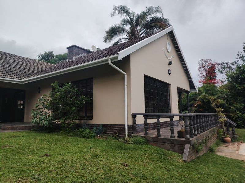 Rear view of the house featuring a tiled roof, brick facade, and a raised patio area with a decorative balustrade and security window bars.