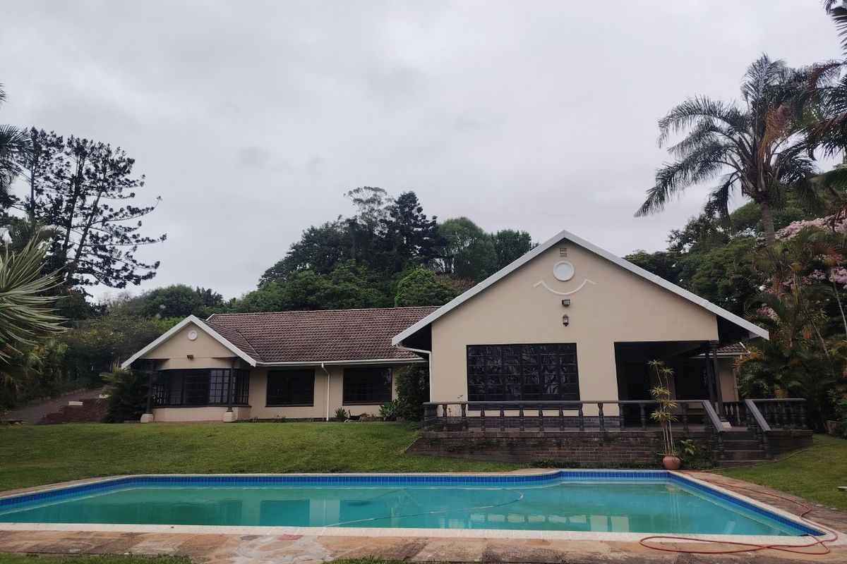 Rear view of the house featuring a swimming pool, patio area with balustrades, and a landscaped garden setting.