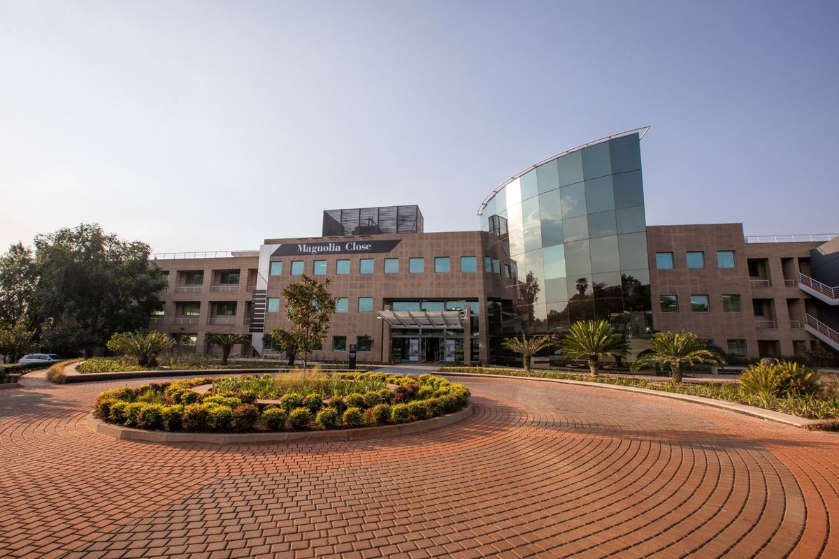 Professional exterior view of Magnolia Close commercial office building featuring a modern glass facade, paved circular driveway, and well-maintained landscaped grounds.