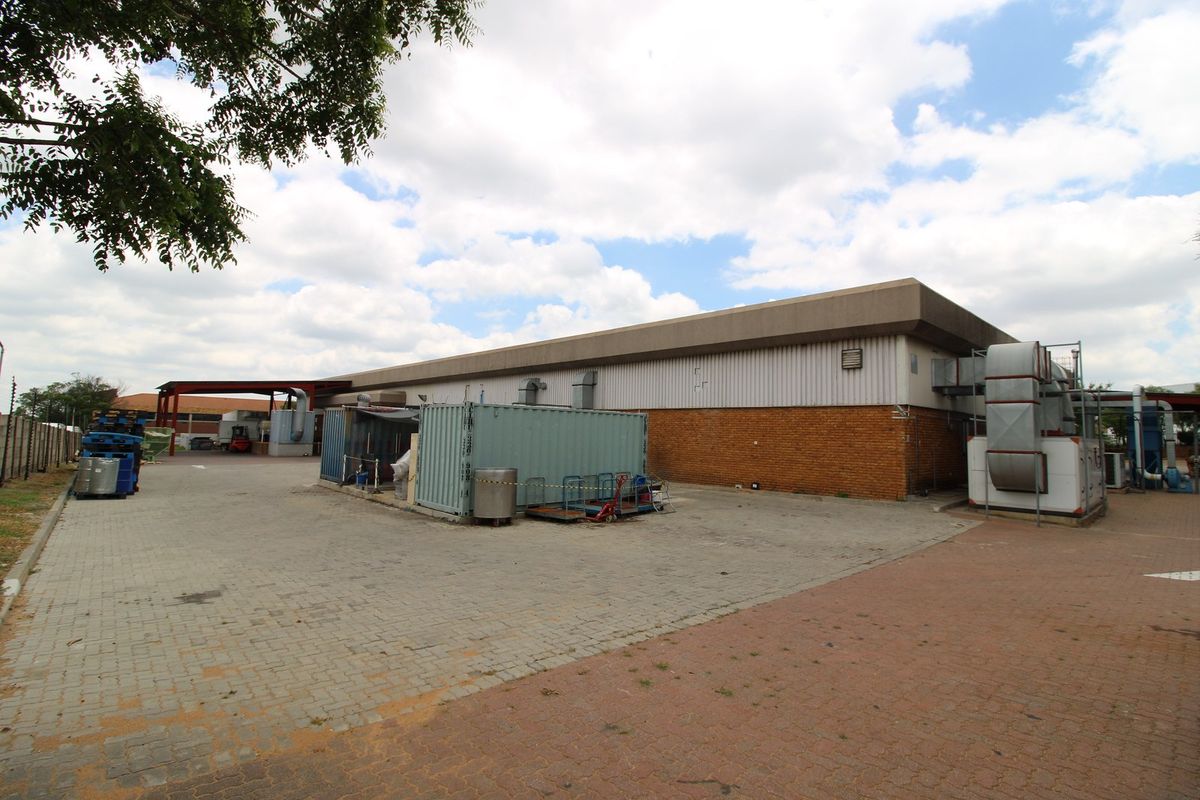 Rear industrial yard featuring paved surfaces, brick and metal cladding, and external HVAC infrastructure.