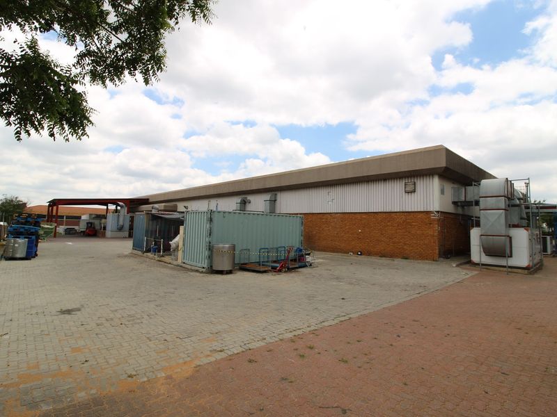 Rear industrial yard featuring paved surfaces, brick and metal cladding, and external HVAC infrastructure.