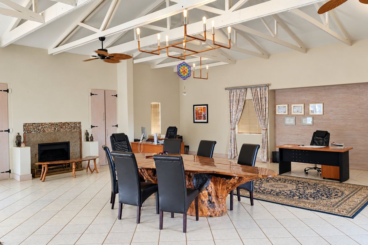 Spacious living area featuring high vaulted ceilings with exposed timber trusses, tiled flooring, and a prominent built-in fireplace.