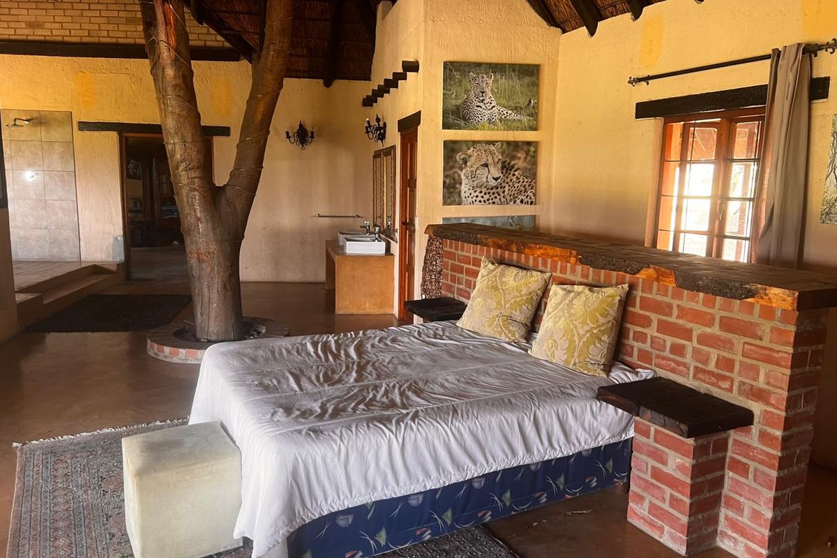 Unique bedroom featuring a thatched roof, exposed brick elements, and an integrated tree trunk, creating a rustic and natural aesthetic.