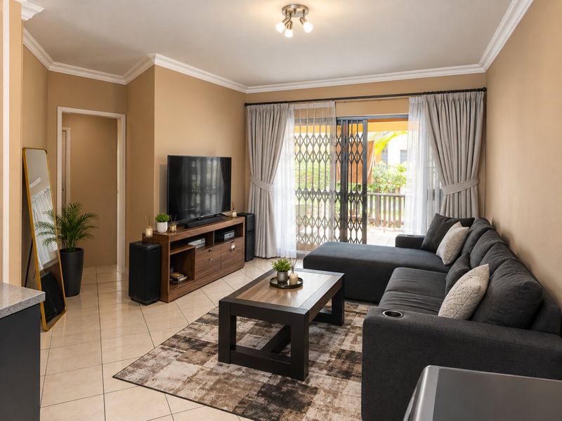 A well-maintained living room featuring tiled flooring, crown molding, and a sliding glass door providing access to an outdoor patio area.