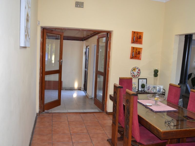 Dining room featuring terracotta floor tiles and double wooden doors leading to an adjacent space, with a built-in fireplace visible in the corner.