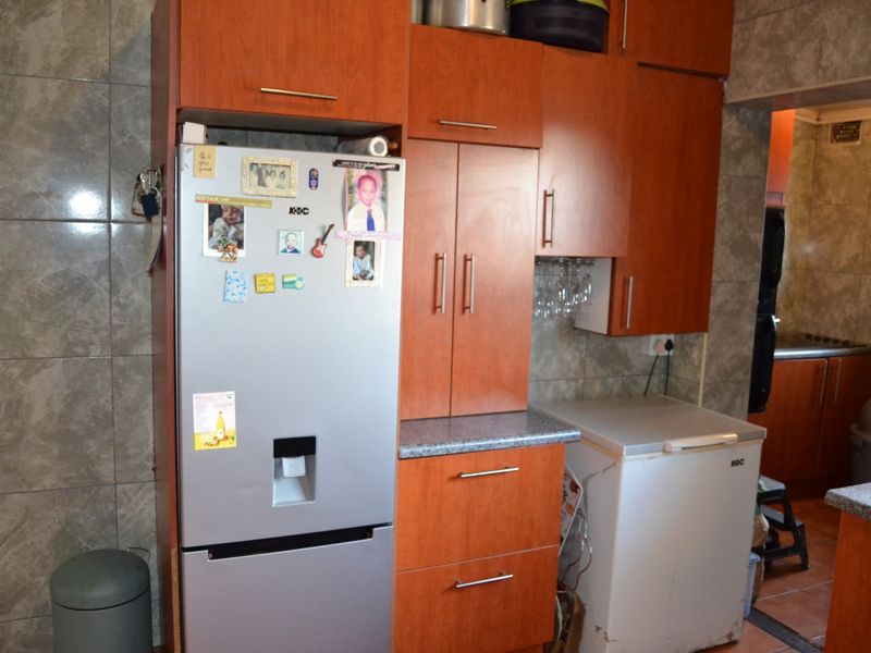 A functional kitchen area featuring wood-finish built-in cabinetry, laminate countertops, and tiled wall surfaces.