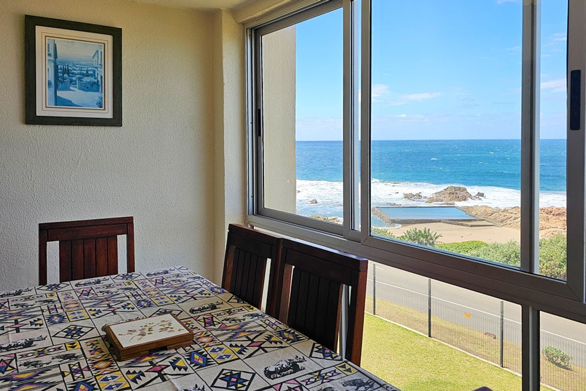 Dining area featuring large sliding windows that offer expansive, unobstructed views of the ocean and coastline.