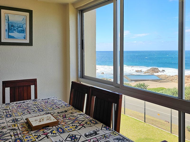 Dining area featuring large sliding windows that offer expansive, unobstructed views of the ocean and coastline.